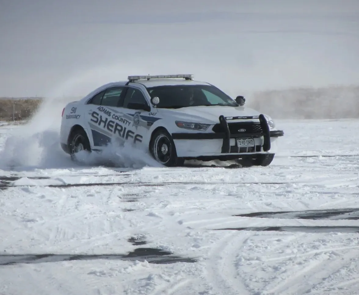 Adams County Sheriff patrol car driving through snow-covered road