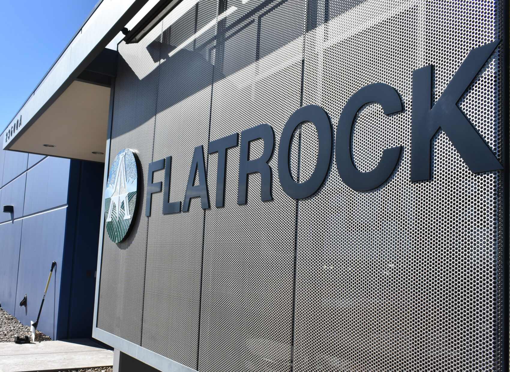 Flatrock sign on perforated metal wall with blue building facade