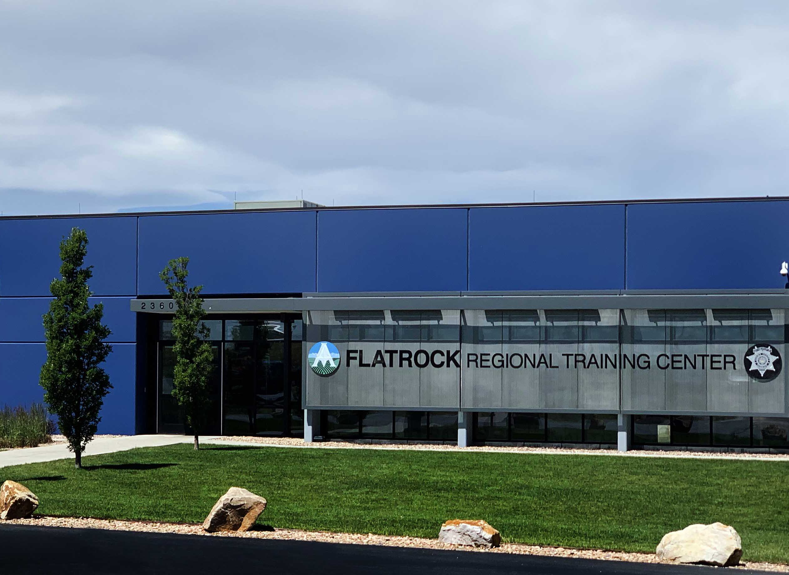 Flatrock Regional Training Center building with flags and trees, clear sky