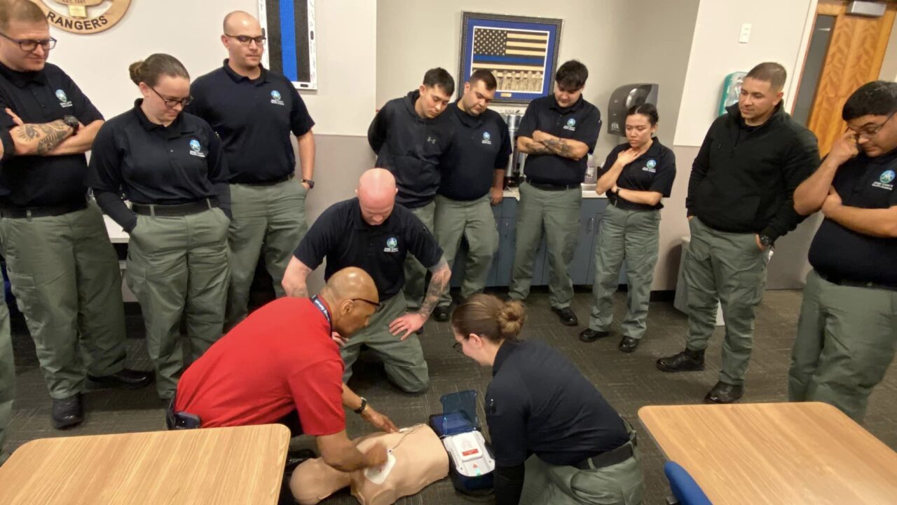 Training session on CPR techniques by uniformed officers, Colorado Rangers patch visible