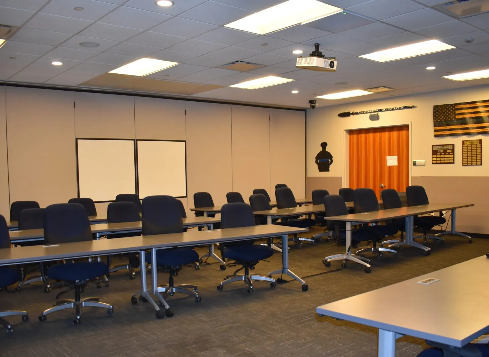 Classroom-A.jpg shows an empty training room with rows of tables and chairs, a projector, and wall decorations including plaques and flags.