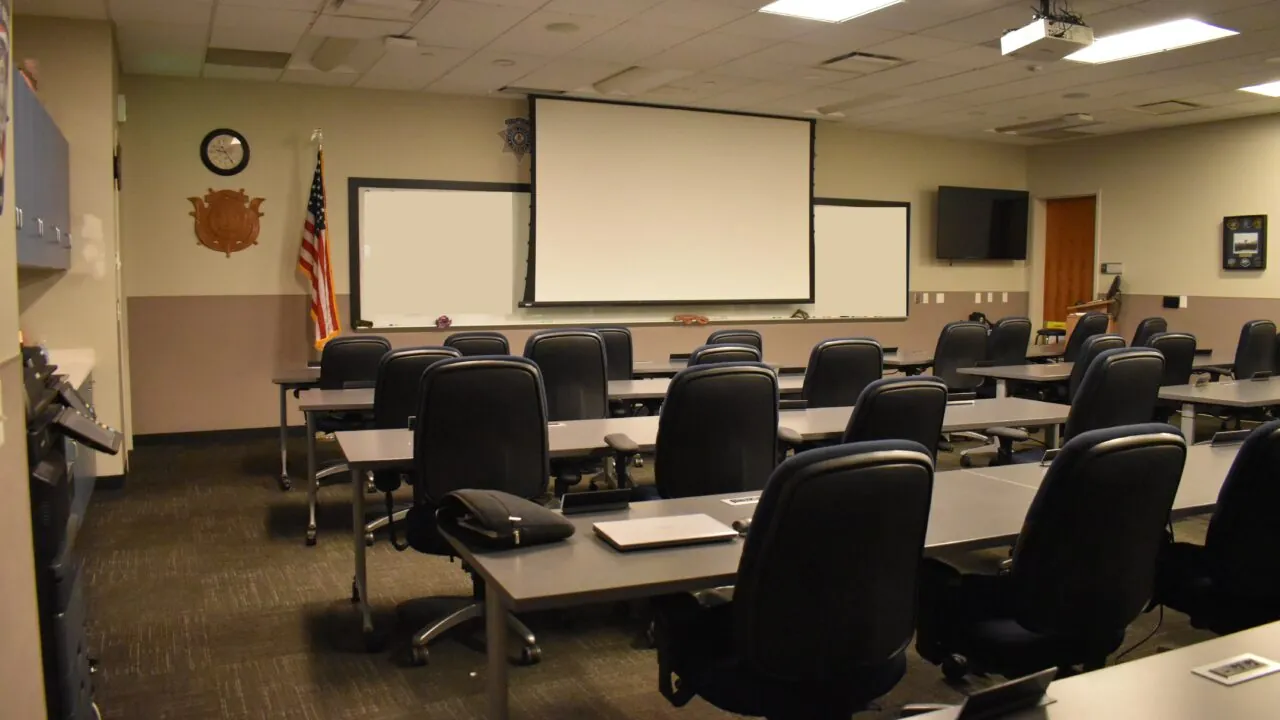 Empty classroom with rows of chairs, projector, and American flag