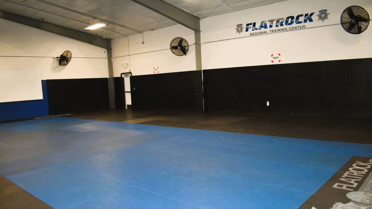 Empty training room with blue mats and "Flatrock Regional Training Center" text on wall
