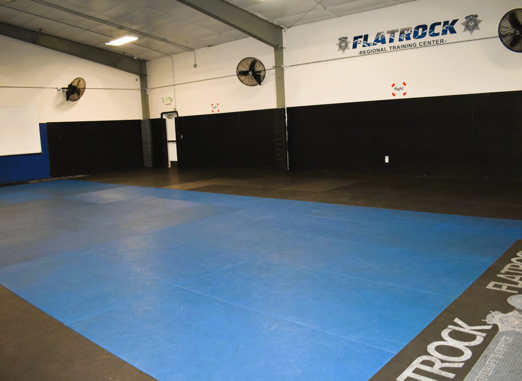 Empty training room with blue mats and "Flatrock Regional Training Center" text on wall