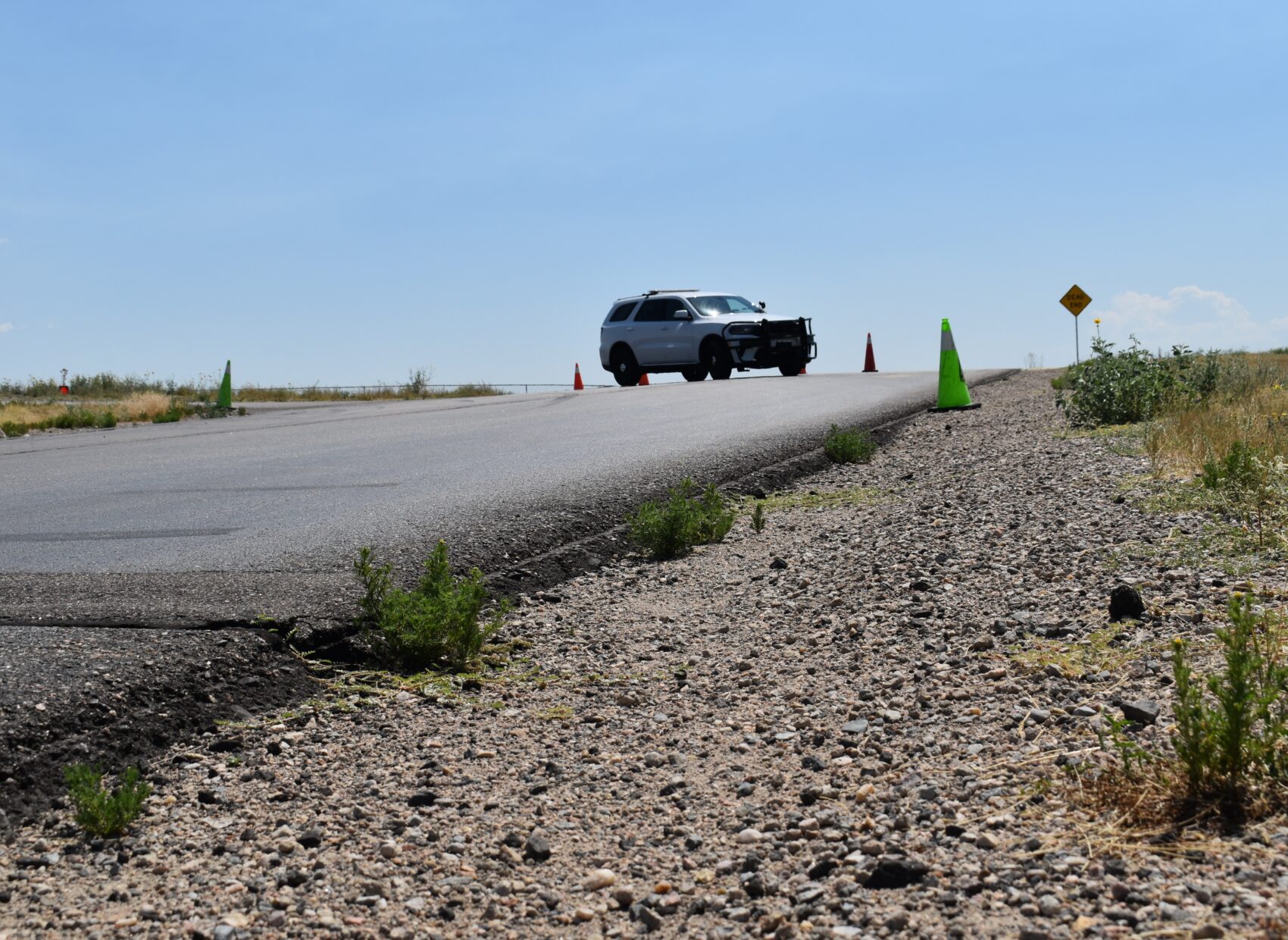 Vehicle on rural road surrounded by traffic cones and gravel shoulder