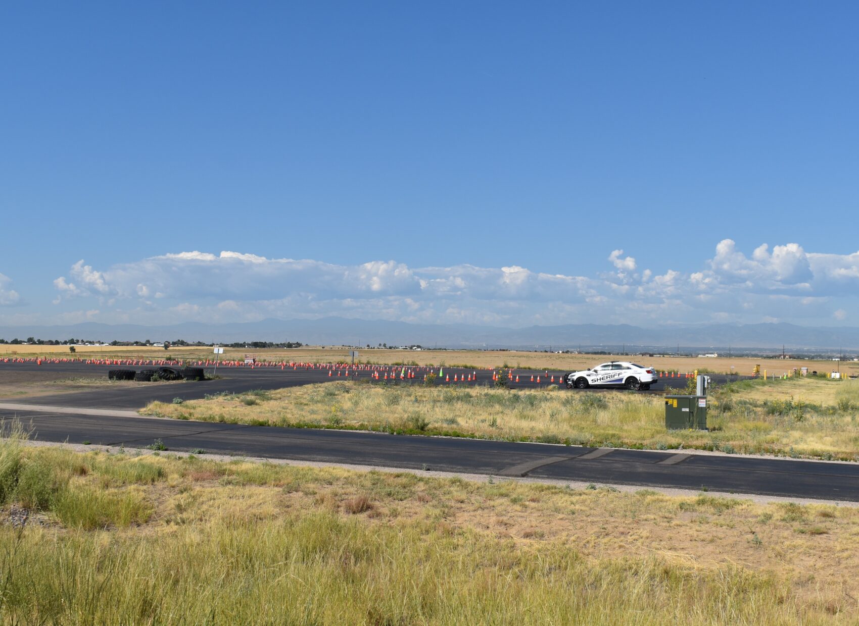 Sheriff car on rural road near traffic cones and mountains in the background